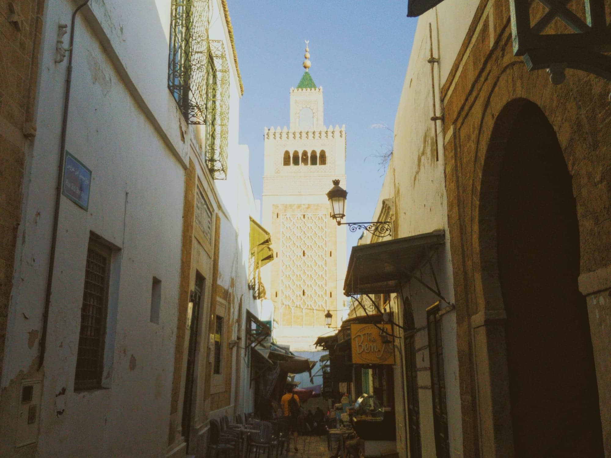 A medina alley framing the Zitouna minaret in golden light